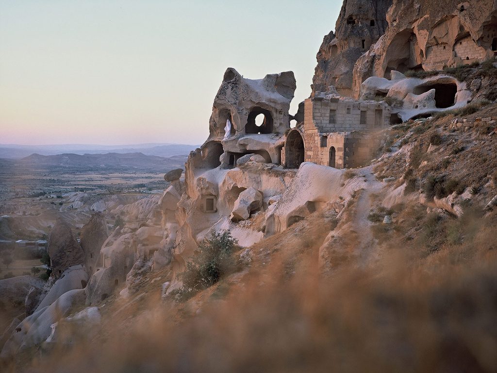 Stone houses with windows, blending seamlessly into the rocky landscape.