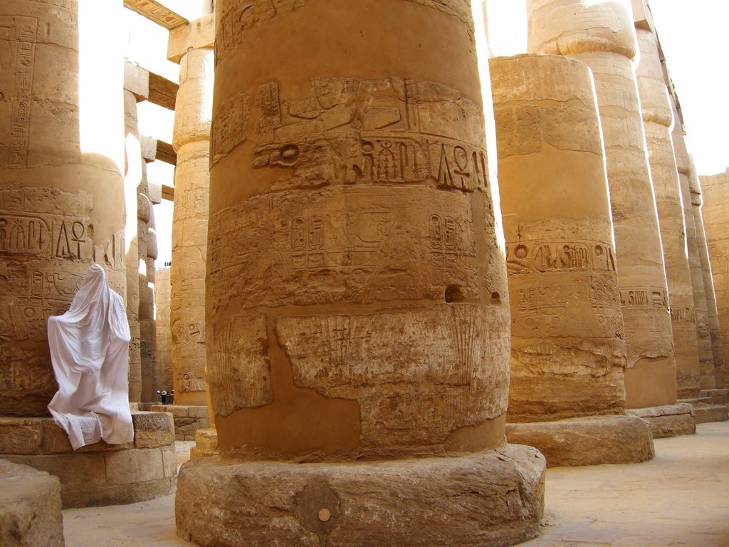 A person standing in front of a tall pillars, creating a sense of scale and grandeur.