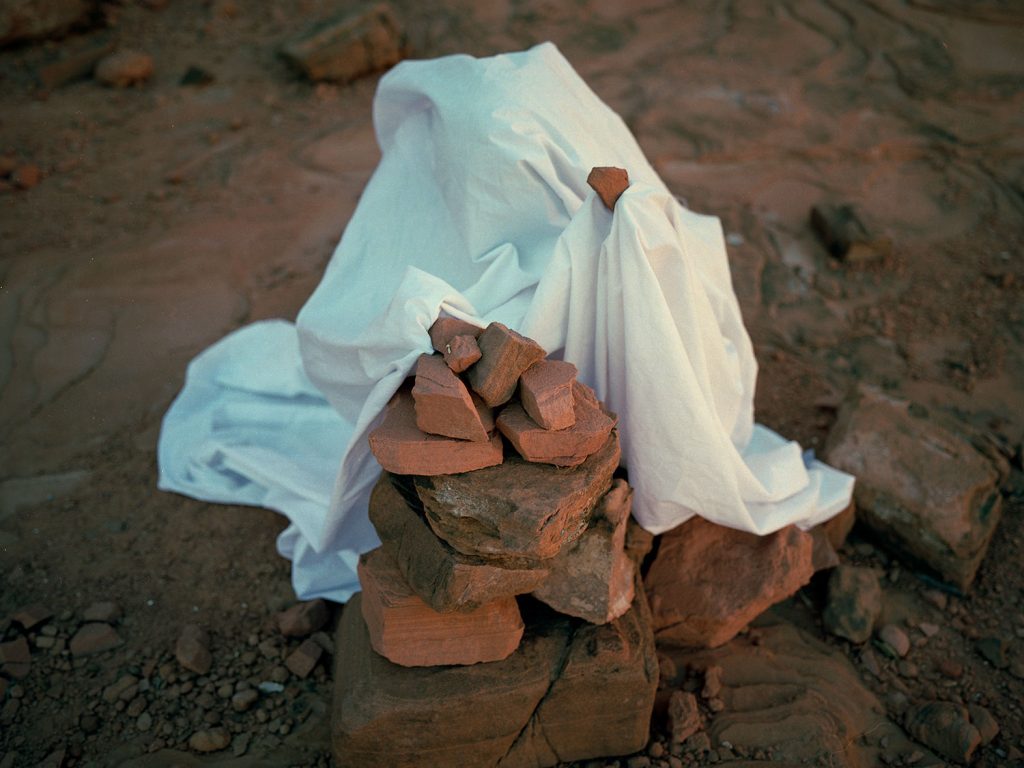 A person draped with white robe and over rock creating a scene