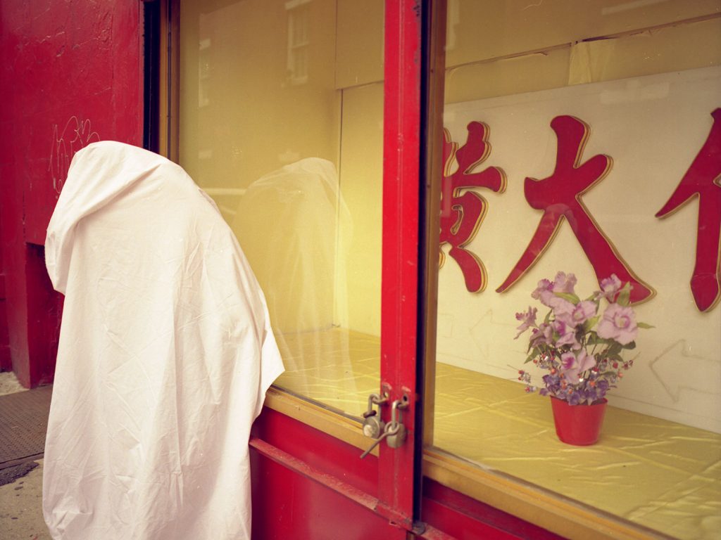 A person standing in a private room draped white cloths.