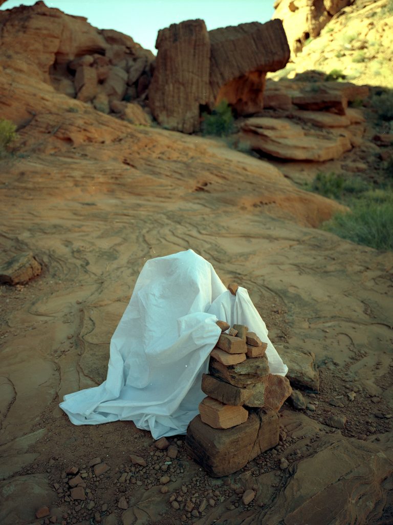 A person draped with white robe make stack of rock.