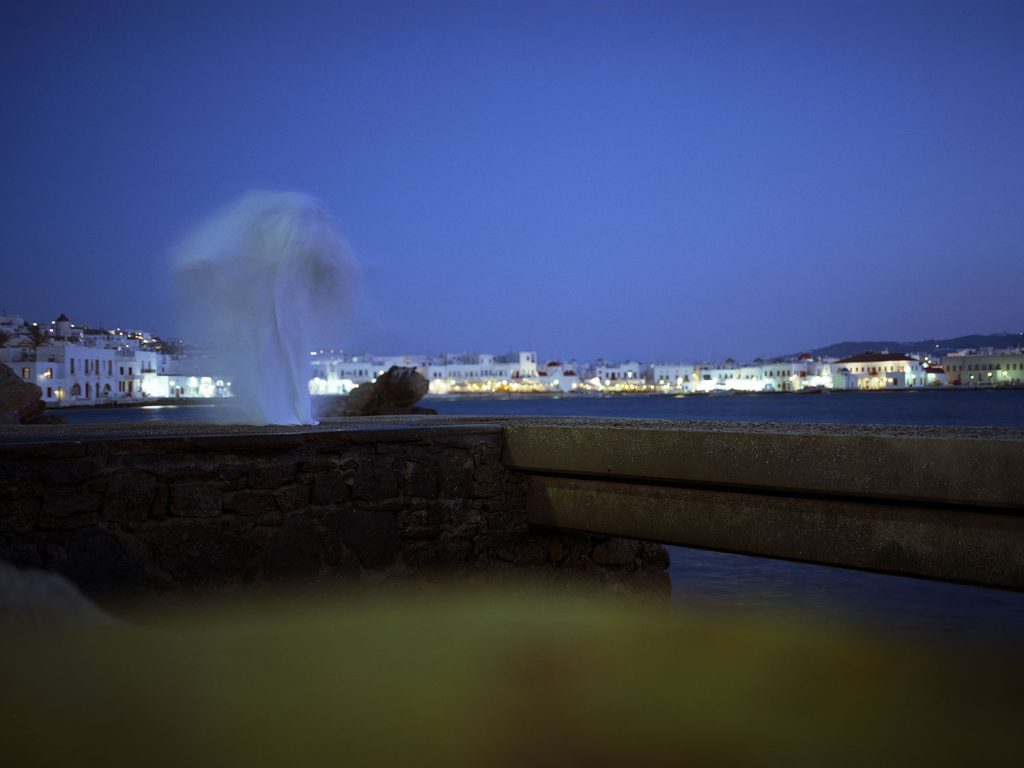 A ghostly figure standing on a pier at night, looking out into the dark waters.