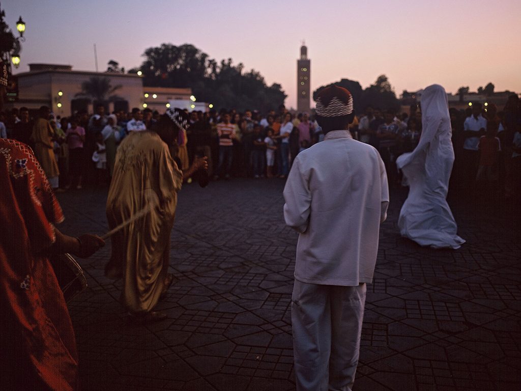 A group of people in white and traditional attire standing in a courtyard, showcasing cultural diversity.