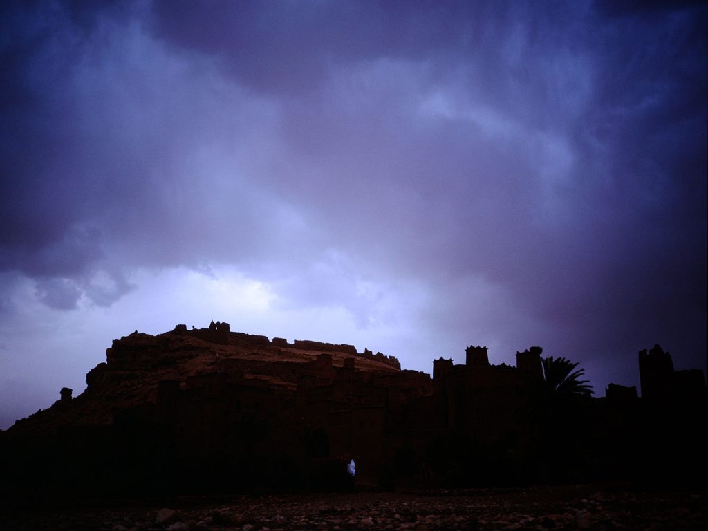 A castle in the desert beneath a dark stormy sky.