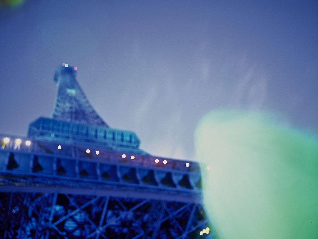 A nighttime view of the Eiffel Tower and a personwear white robe slightly blurred.