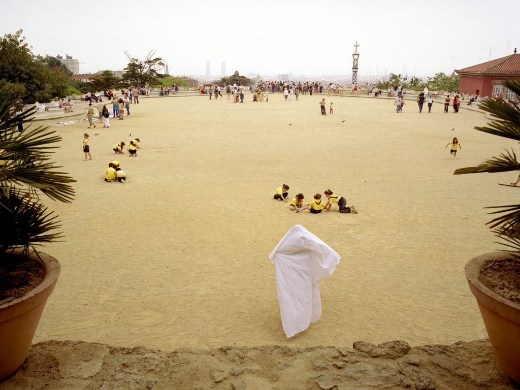 A person wearing white cloth on the ground in a serene park, adding a touch of natural surroundings