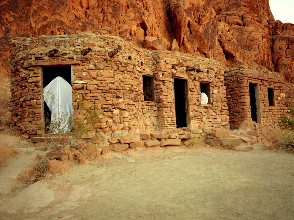 A person draped white robe standing inside a stone building