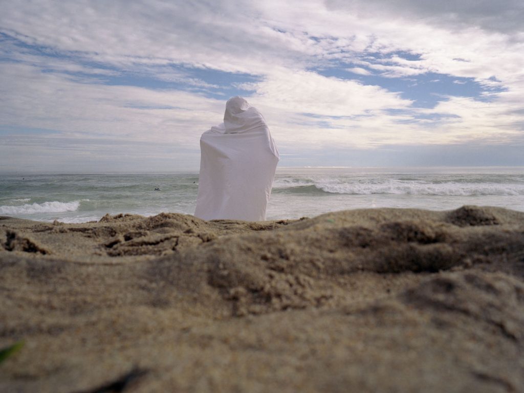 A person sitting on a sandy beach, enjoying the serene view of the ocean waves crashing onto the shore.