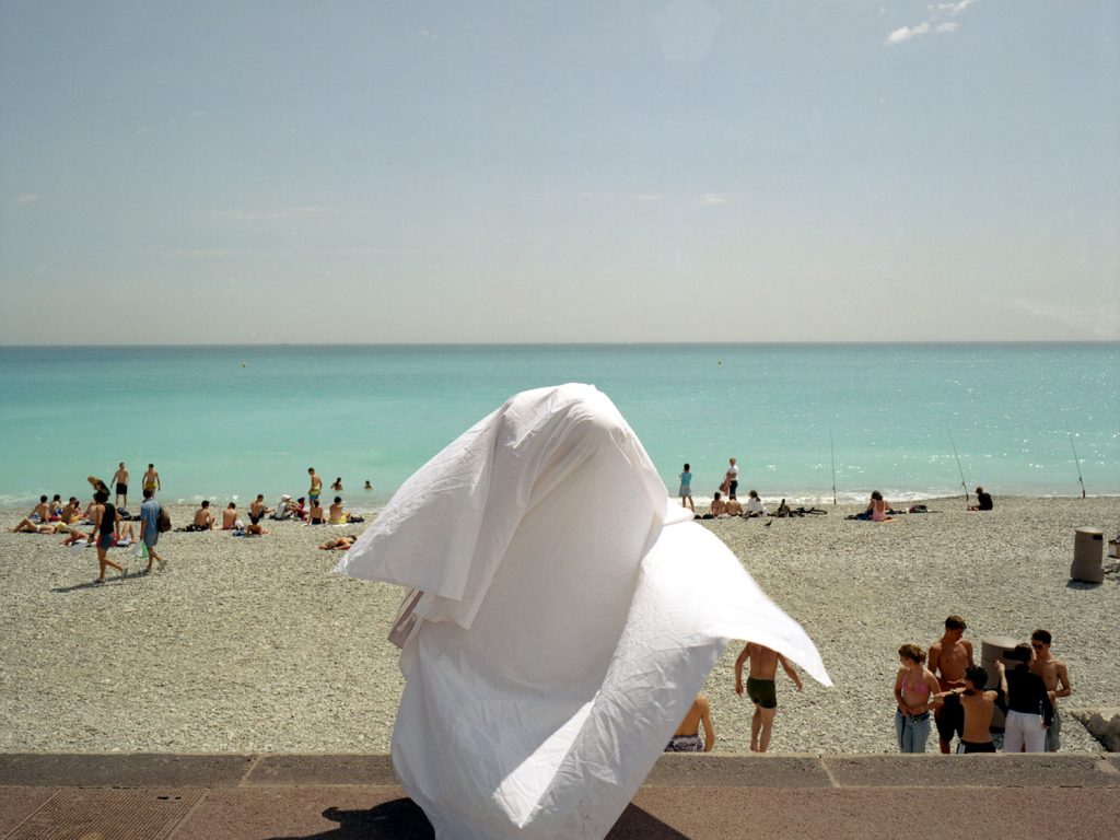 A person standing on a beach with a white robe, enjoying the serene view of the ocean waves.