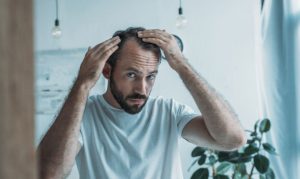 Worried man watching reducing hairline