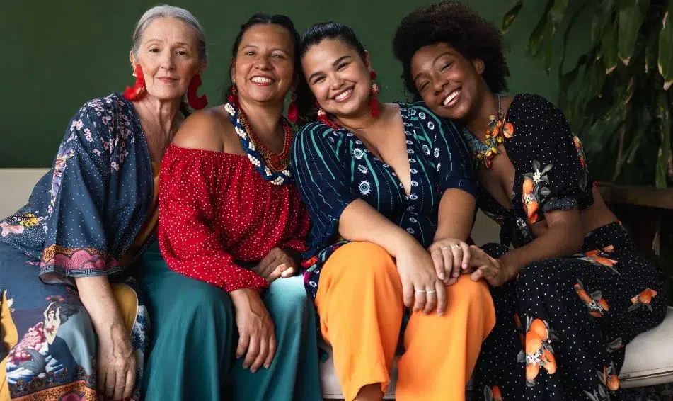 Four women sitting together on a couch, sharing a moment of friendship and beauty tips