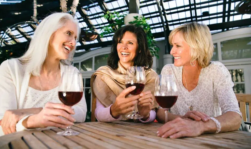 Three women enjoying wine at an outdoor table, showcasing a relaxed and social atmosphere